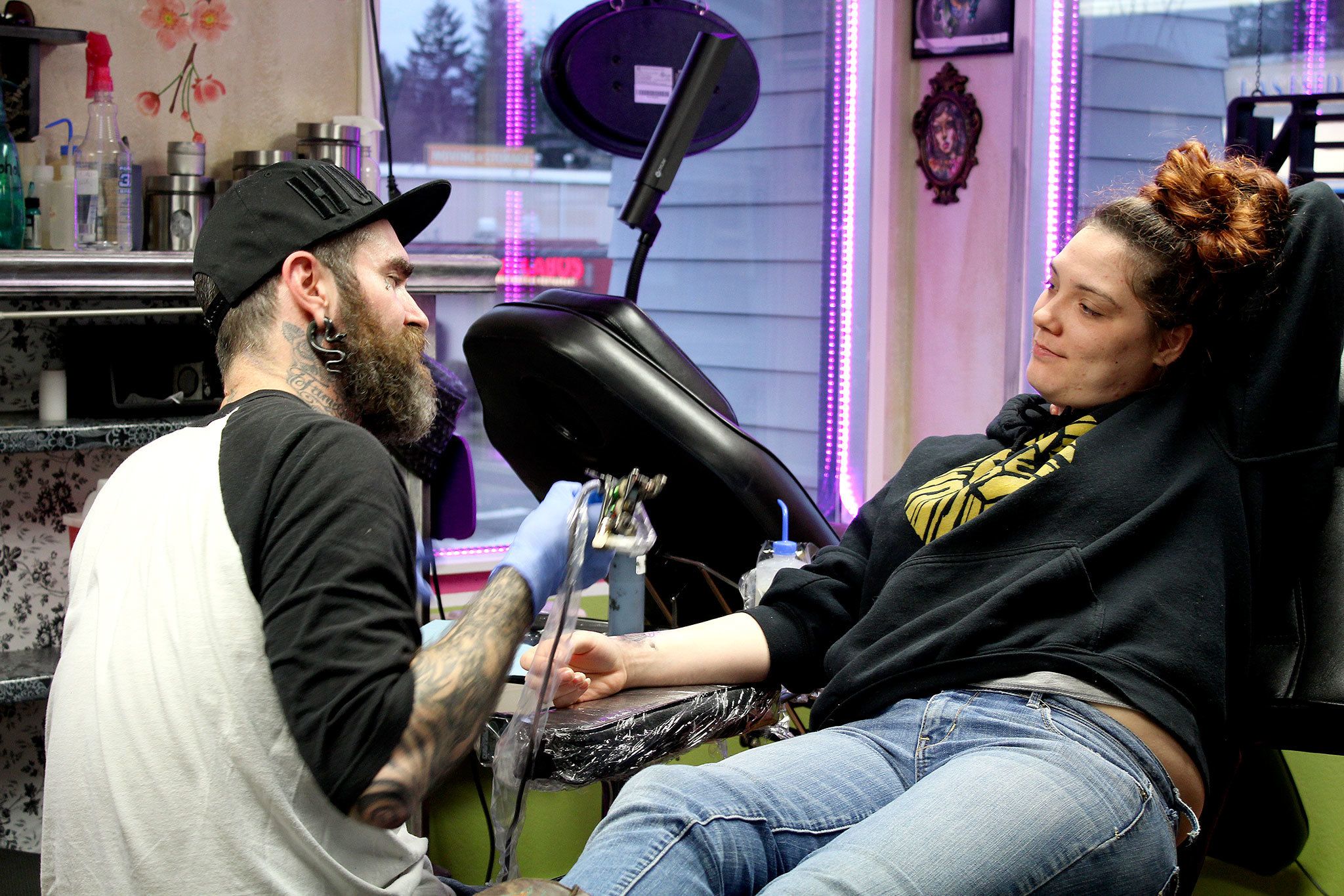 Paul Weaver tattoos Chelsey Freeman with flash art. Michelle Beahm / Kitsap News Group