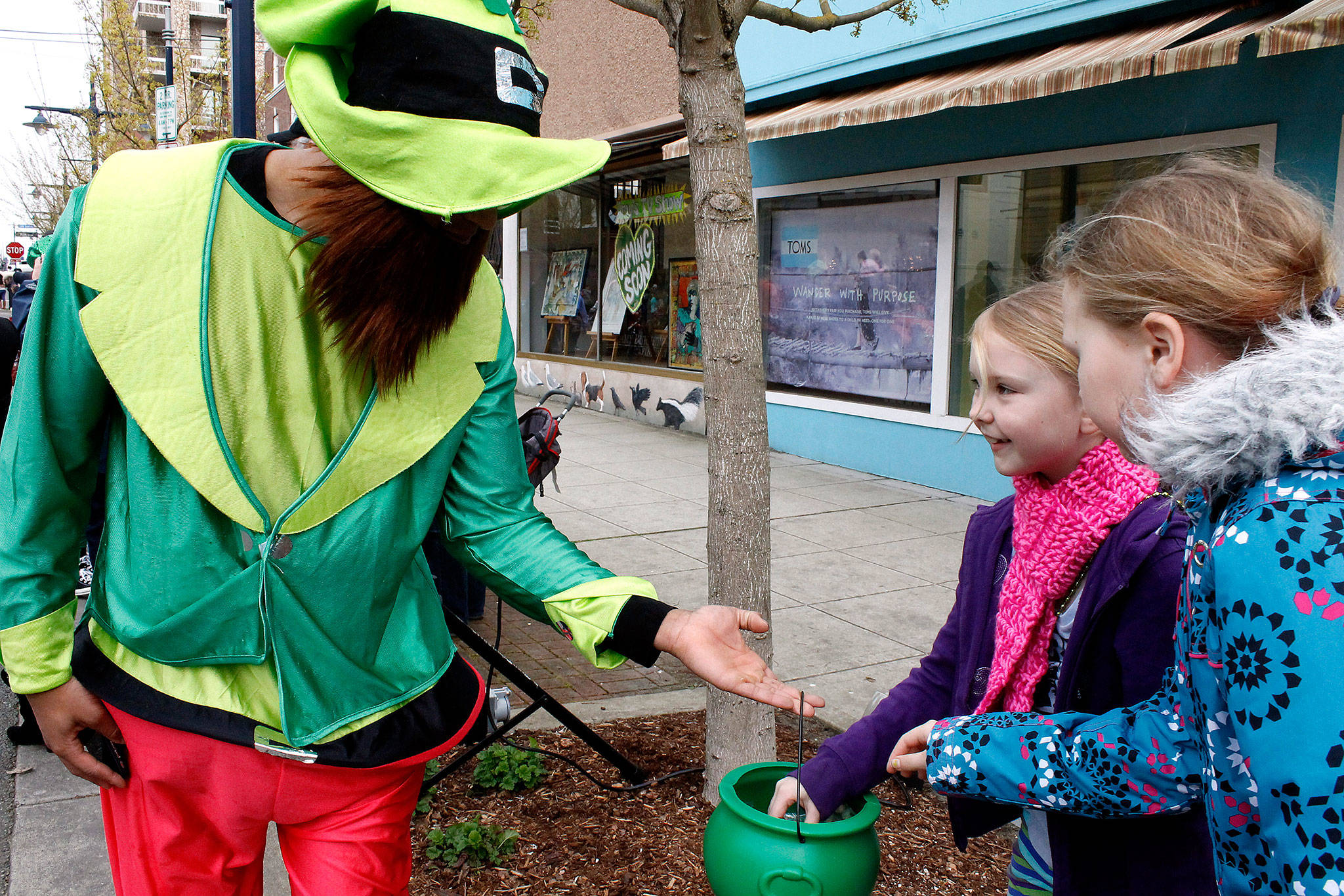 Girls spectating the 2016 Bremerton St. Patrick’s Day parade receive gold coins from a participant.                                Michelle Beahm / Kitsap News Group