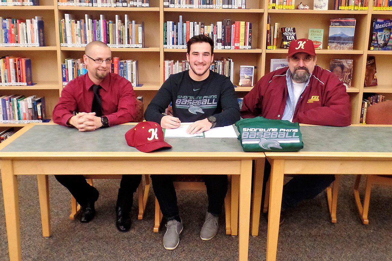 Anderson Crawford, middle, smiles as he signs with Shoreline Community College. Kingston head baseball coach Abe Lupkin, left, and coach Jack Nannery look on. (Richard Henert / Contributed)