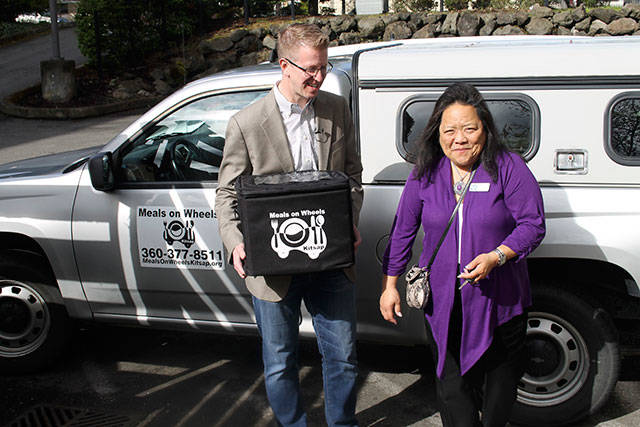 Rep. Kilmer holds a hot meal box as he and Meals on Wheels Kitsap Executive Director Deborah Horn prepare to drive to Ed’s home. (Terryl Asla/Kitsap News Group)