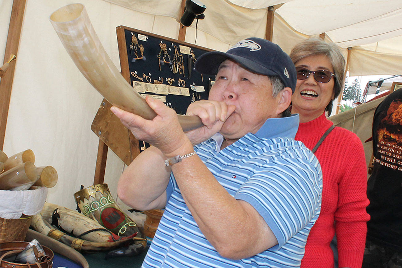 Chi-Mei Tai shows some skill with a Norwegian blowing horn, May 19 at Viking Fest. Richard Walker/Kitsap News Group