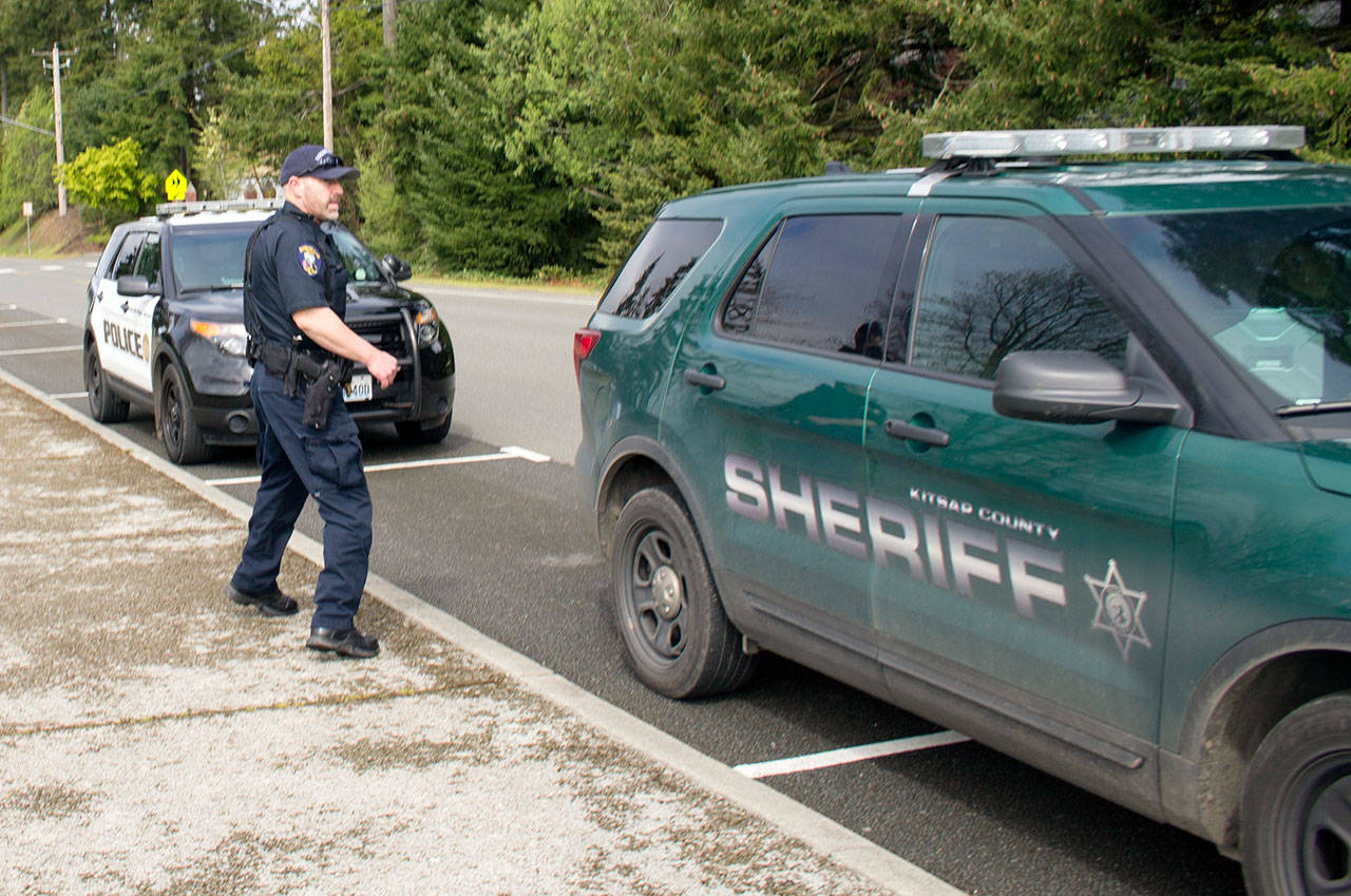 Officers investigating near the North Kitsap High School sports field run to their cars to investigate a lead on the other side of the campus, May 2. (Sophie Bonomi/Kitsap News Group)