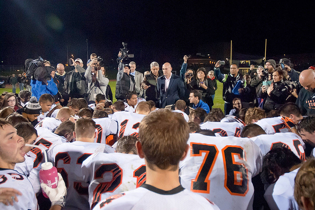 Dozens of Centralia High School football players surround Joe Kennedy, then-assistant football coach, for a prayer on the 50-yard line Oct. 16, 2015. Judge M. Smith, 9th Circuit Court of Appeals, brought up this photo when Kennedy’s lawyer Rebekah Ricketts said they were fighting for Kennedy’s right to “pray quietly and alone.”                                Kitsap News Group file photo