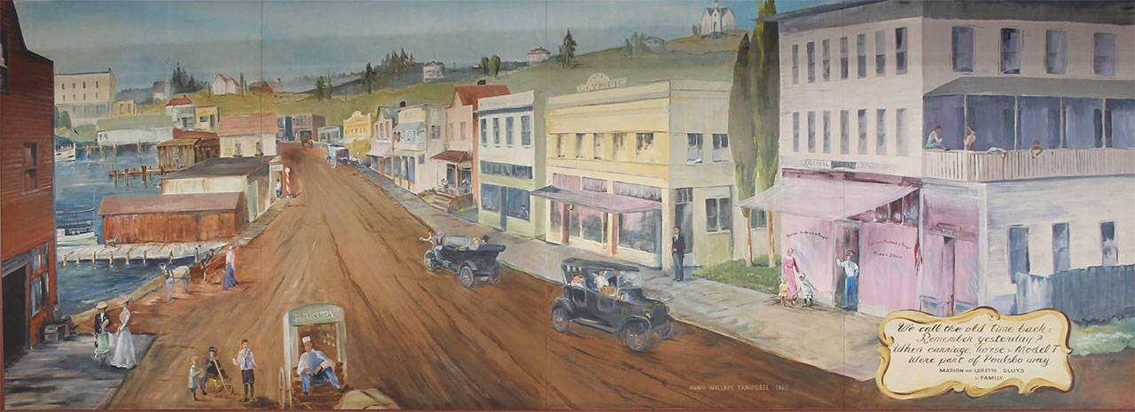 The 1968 mural on the wall in Sluys’ Bakery was done by a local artist, the late Anne Campbell, and depicts Front street in the early 20th century as seen from the curve in the street just past what was then the Olympic Hotel on the right. Notice there was still ocean where the the Muriel Iverson Williams Waterfront Park is today. The man in the bakery wagon in the lower left corner is Marion Sluys.                                Terryl Asla/Kitsap News Group