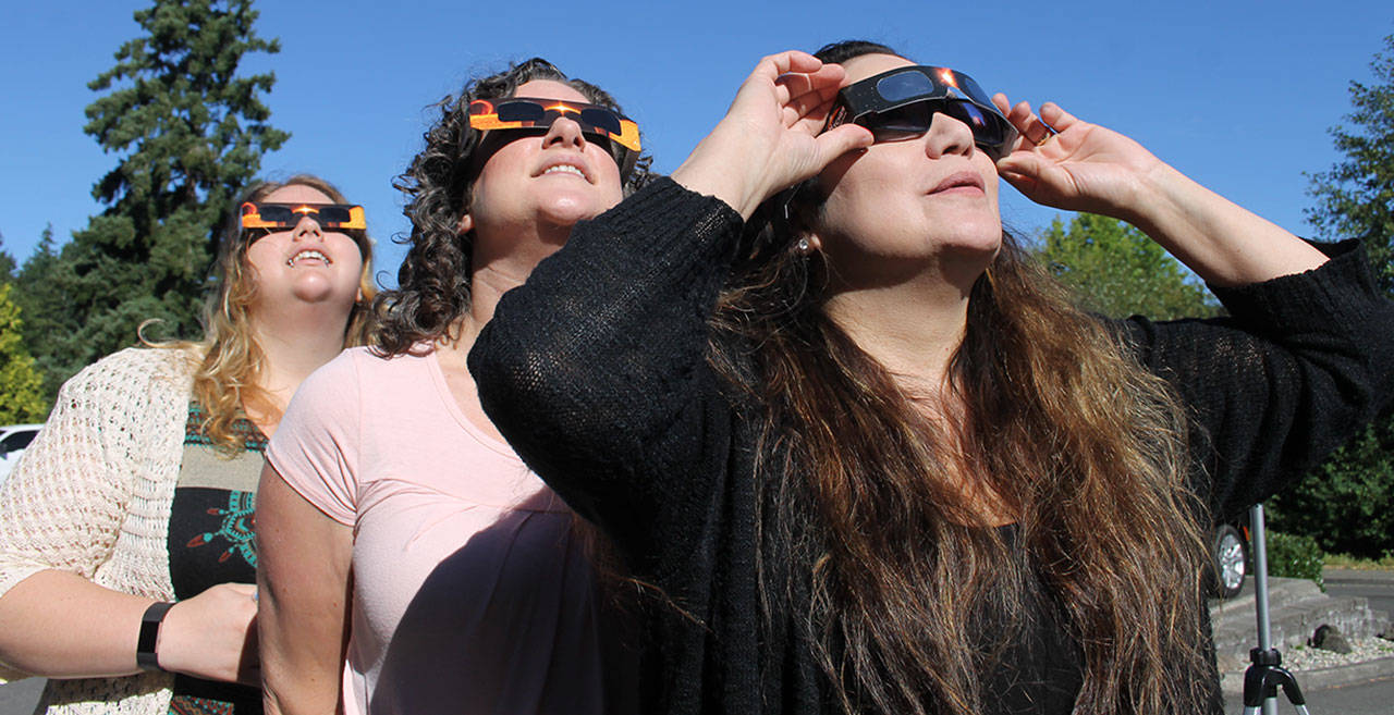 From left, Marika Jones, Kari Jacobs and Priscilla Wakefield of Kitsap News Group watch the partial eclipse Aug. 21 from in front of the news group offices in Poulsbo. (Richard Walker/Kitsap News Group)