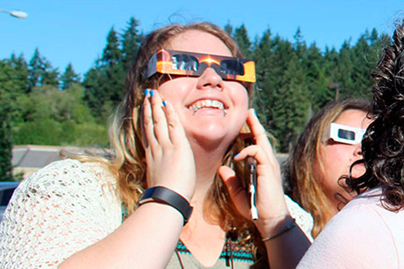 Marika Jones of Kitsap News Group watches the partial eclipse Aug. 21 from in front of the news group offices in Poulsbo. (Richard Walker/Kitsap News Group)