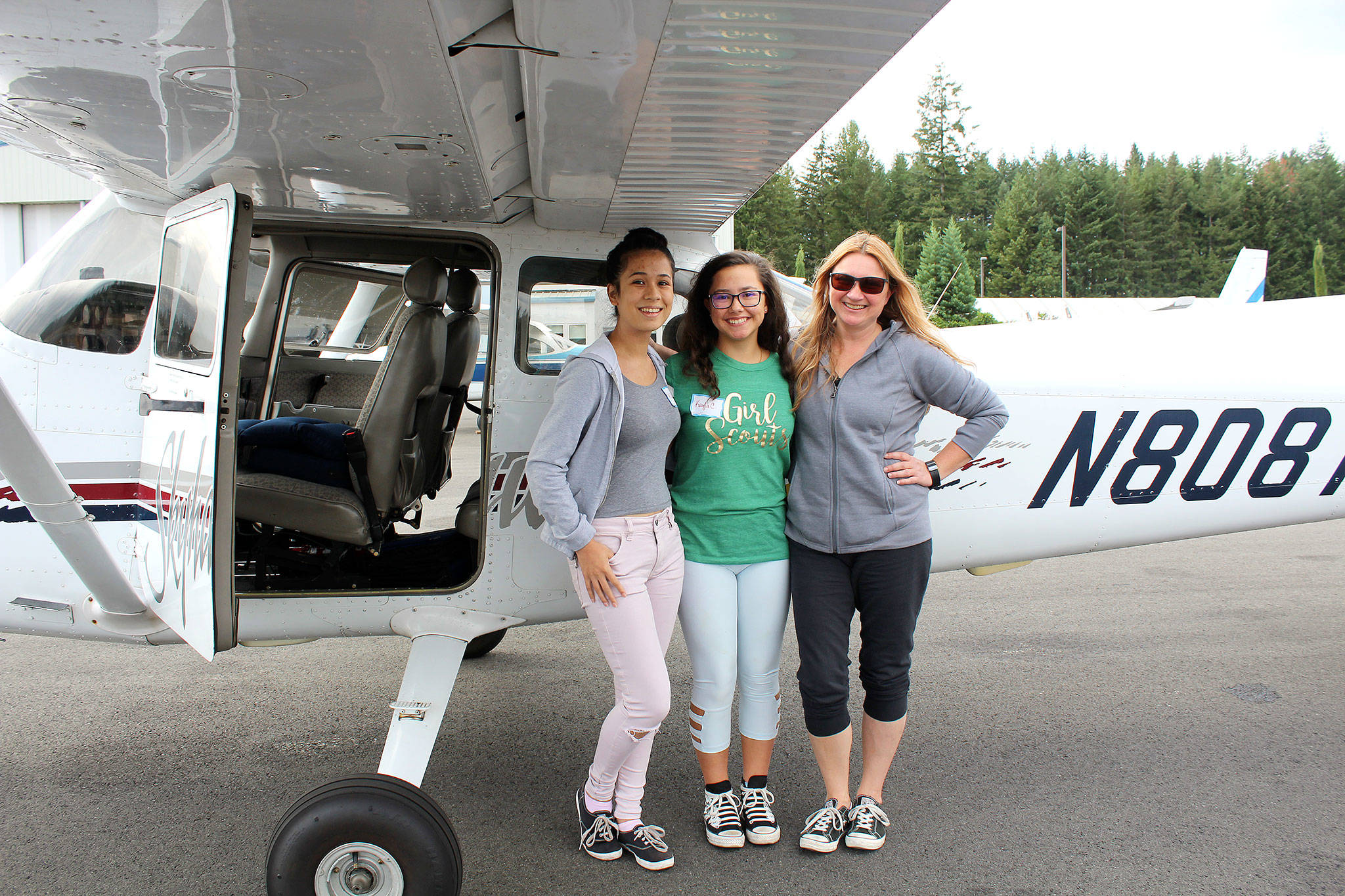 Mikela Arnall, 14, Kayla Cortes, 15, and pilot Mary Suligoy stand on the tarmac outside the plane both teenagers had the chance to fly, thanks to the Discover Aviation Day program through the Girl Scouts of Western Washington.                                Michelle Beahm / Kitsap News Group