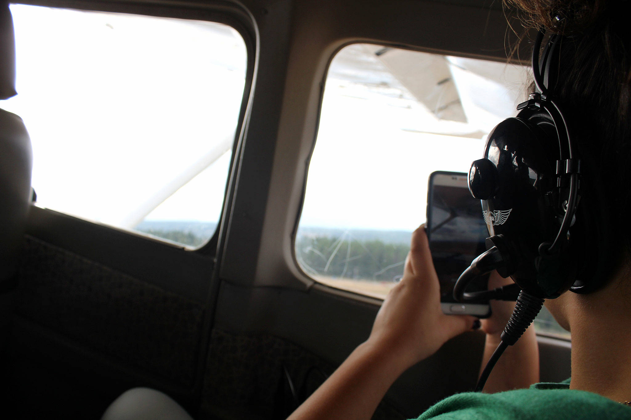 Kayla Cortes, 15, takes photos out the window of the backseat of a plane, piloted by her fellow Girl Scout, Mikela Arnall, 14.                                Michelle Beahm / Kitsap News Group