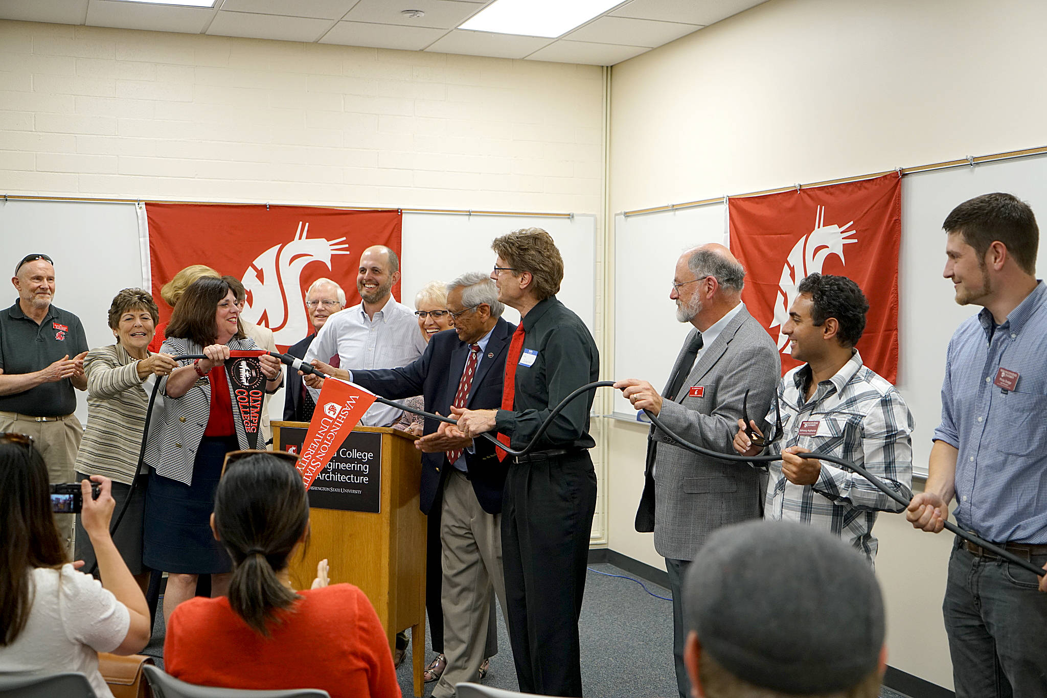 Representatives from Olympic College and Washington State University connect power cables to symbolize the opening of the new electrical engineering building, part of the Bremerton OC campus.                                Photo courtesy Olympic College