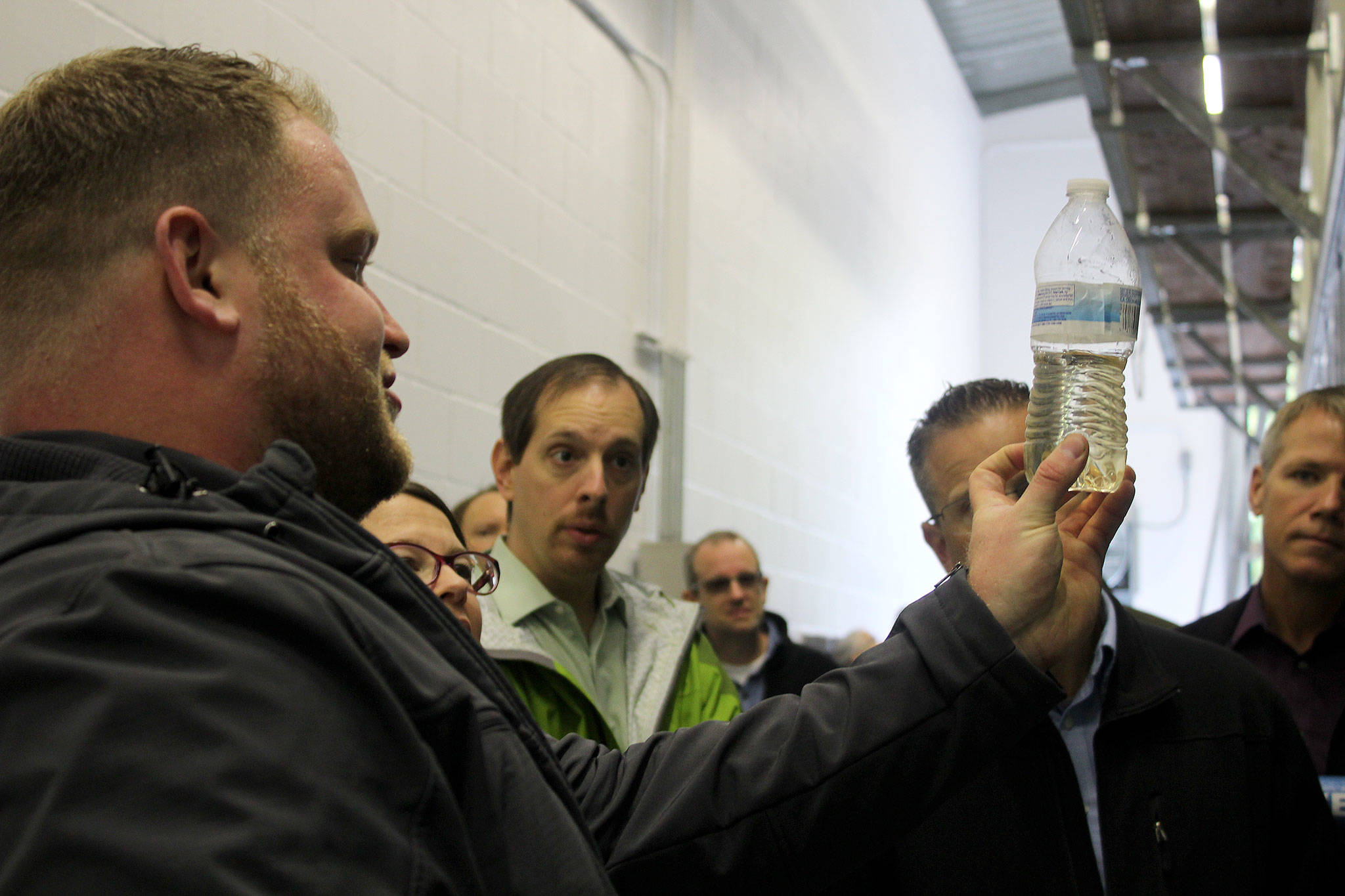Luke Thurston, KPUD staff member, shows a crowd of people what the water looks like after being treated at the Port Gamble Resource Recovery Facility.                                Michelle Beahm / Kitsap News Group