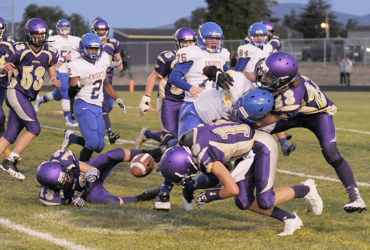 Sequim’s Taig Wiker (13), Nate Despain (10) and Gavin Velarde force Bremerton running back Semaj Cook to fumble in the first quarter of their Olympic League tilt on Sept. 22. (Michael Dashiell/Sequim Gazette)