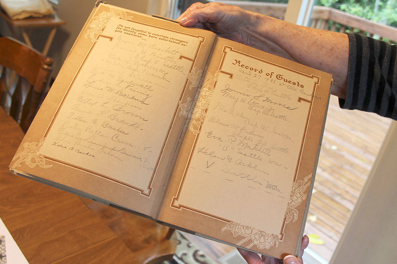 Ione Visick holds a page from 1931 in the P.E.O. chapter’s Record of Guests. (Richard Walker/Kitsap News Group)