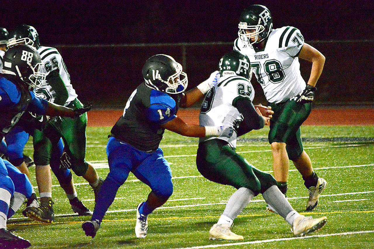 Olympic senior Mason Quitevis (14) pulls down Port Angeles running back Jake Allen (29) behind the line of scrimmage during the Trojans’ 59-13 win on Senior Night.