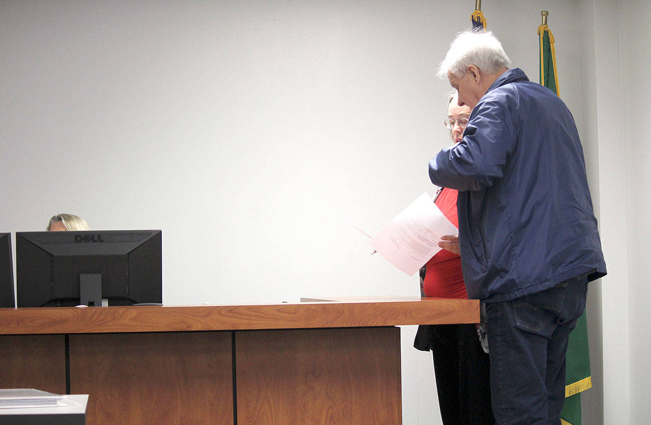 Kerry Stevens and Larry Mann receive a copy of the temporary protection orders, keeping Mann away from Karst Brandsma and Magnalyna Geisler until a final decision is announced Nov. 1.                                (Photo: Michelle Beahm | Kitsap Daily News)