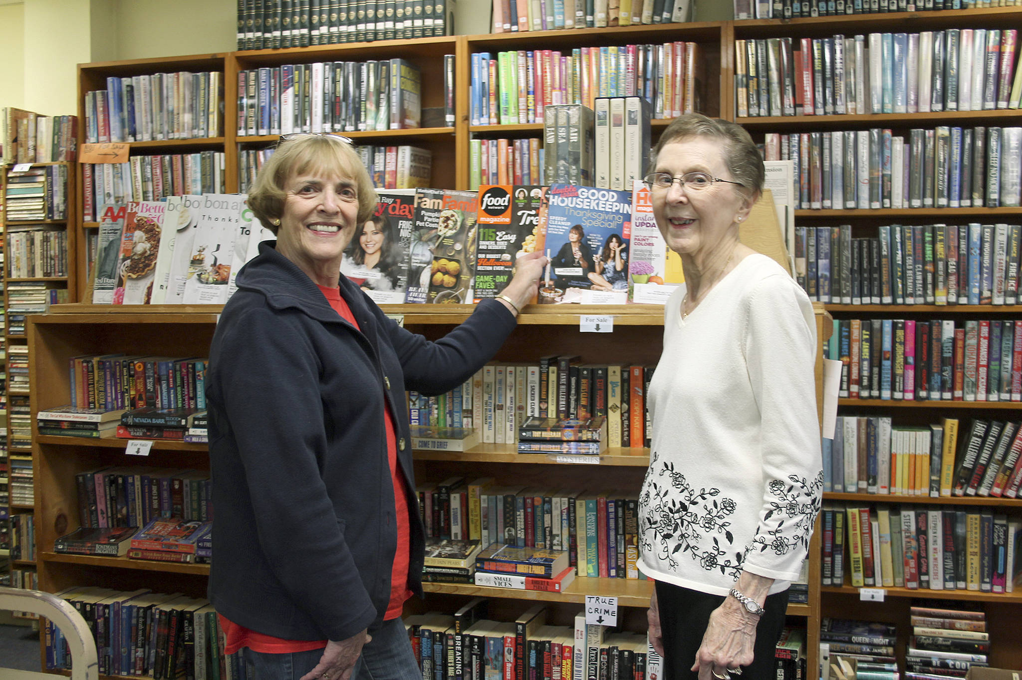 From left, volunteers Bonnie Chrey and Katherine Smith pose near the selection of magazines at the Tracyton Library. (Leslie Kelly/Kitsap News Group)