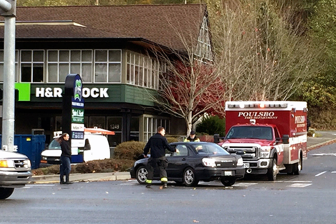 Poulsbo fire fighters assist at the scene of a vehicle collision on Highway 305 and Liberty Road, Nov. 13. The cause of the crash was not immediately known, but it coincided with traffic signals losing electrical power, presumably because of the wind storm. (Nick Twietmeyer/Kitsap News Group)