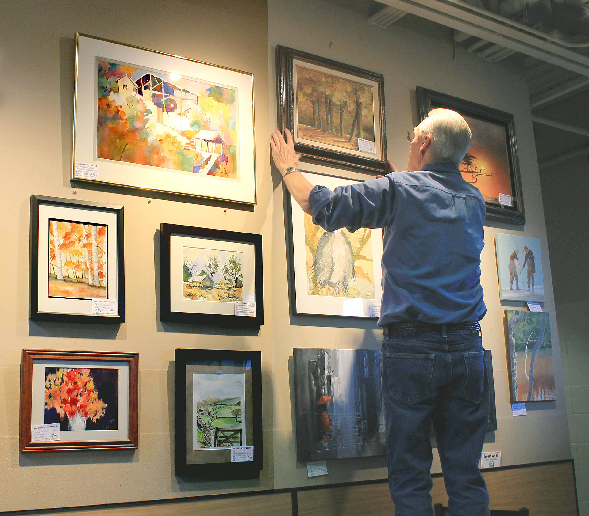 Garven Kinley places PAL paintings on Central Market’s upstairs wall.