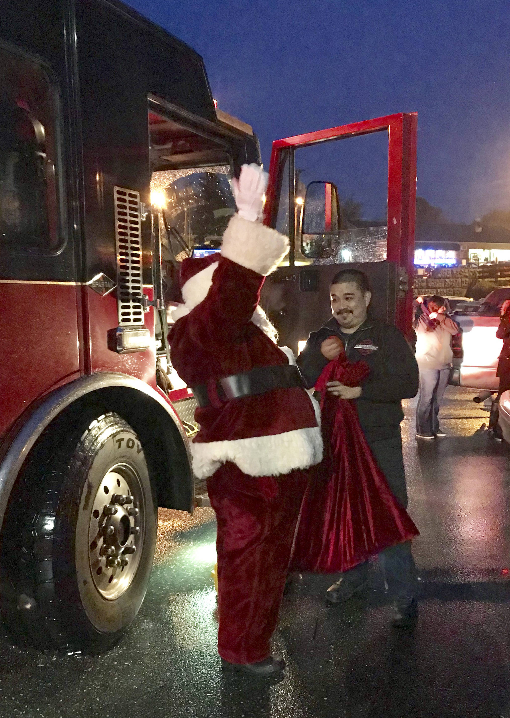 &lt;em&gt;NKF&R Lieutenant Kris Osera hands Santa his bag of treats after bringing the jolly ol’ elf (and Kitsap News Group reporter Nick Twietmeyer) on one of the district’s fire engines to the Kingston Christmas on the Cove festivities, Dec. 2 at the Port of Kingston. &lt;/em&gt;Michèle Laboda/NKF&R