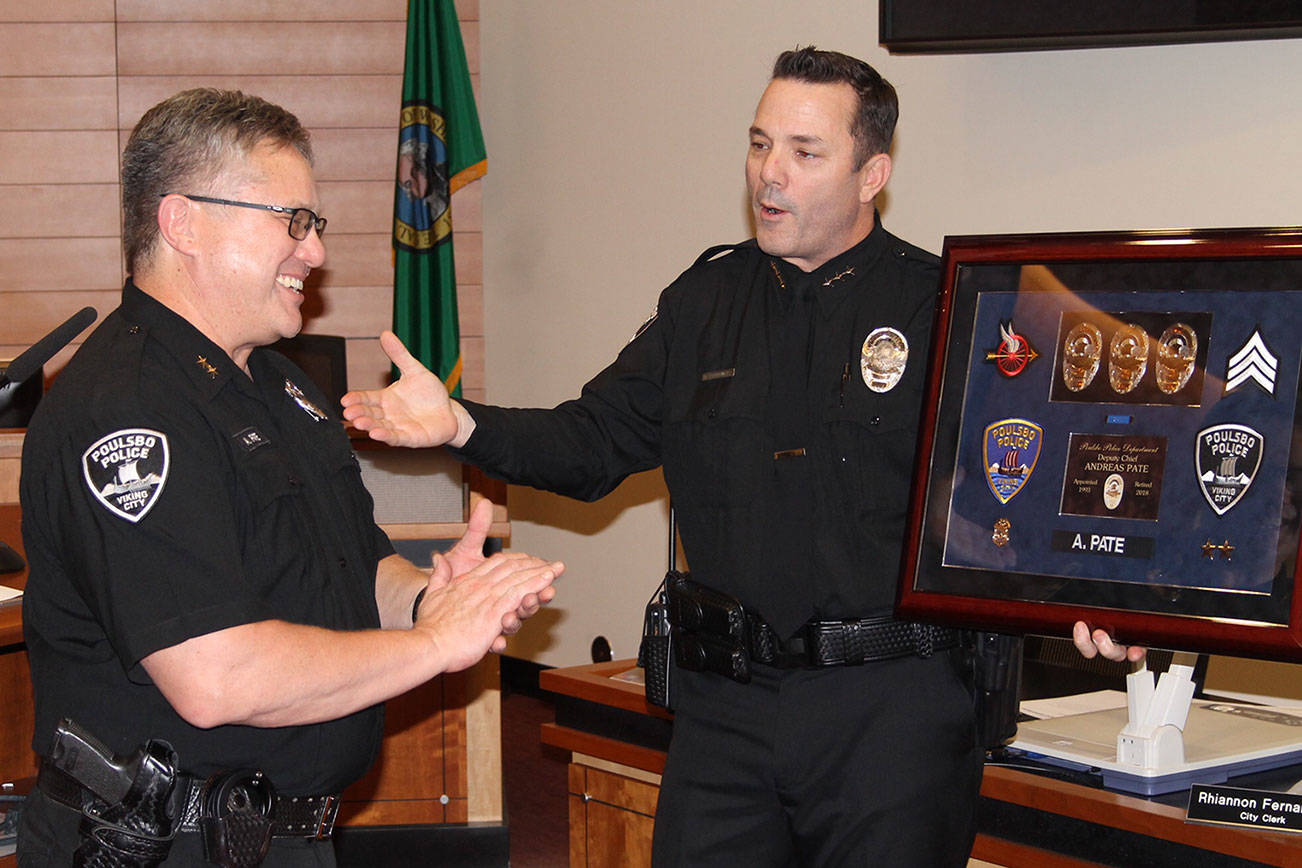 Deputy Police Chief Andy Pate receives a shadow box from Poulsbo Police Chief Dan Schoonmaker in recognition of Pate’s career with the department. Nick Twietmeyer/Kitsap News Group.