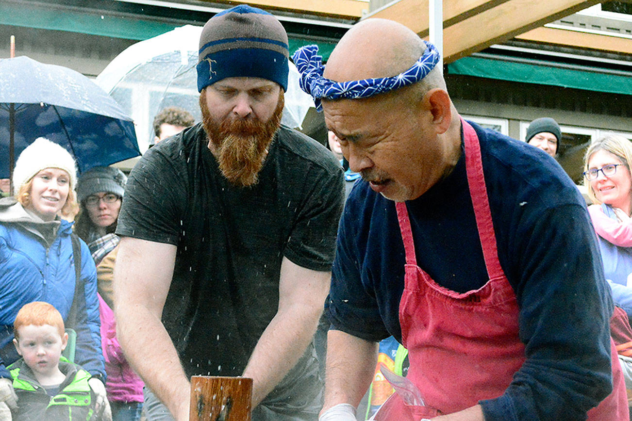 Jason Canfield pounds the mochi with a mallet at the instruction of mochi master Shoichio Sugiyama. (Mark Krulish/Kitsap News Group)