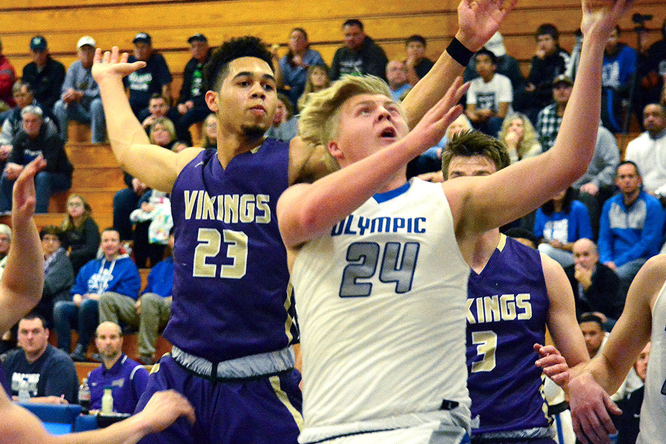 Olympic’s Greg Brehmer (24) goes up for a basket as North Kitsap’s Shaa Humphrey (23) tries to block it. Brehmer scored ten points for the Trojans and was one of many players who stepped up in the 55-50 victory. (Mark Krulish/Kitsap News Group)