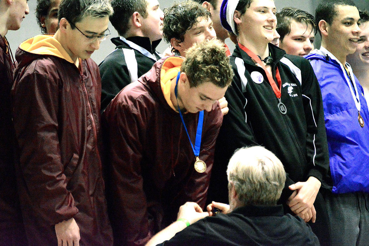 Kingston swimmer Ethan Fox receives a medal from head coach Mark VanHuis after he and his fellow teammates set a new state record in the 200-yard medley relay. (Mark Krulish/Kitsap News Group)