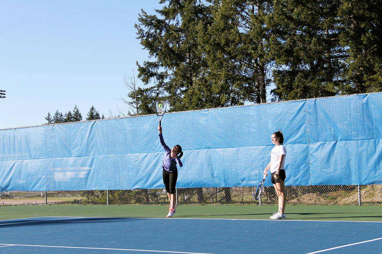 Junior Sydney Troy, right, watches as senior Brooklyn Haro serves the ball in a March 6 practice at the Olympic High School tennis courts. Haro and Troy went to state last year as a doubles team. Jacob Moore | Kitsap News Group