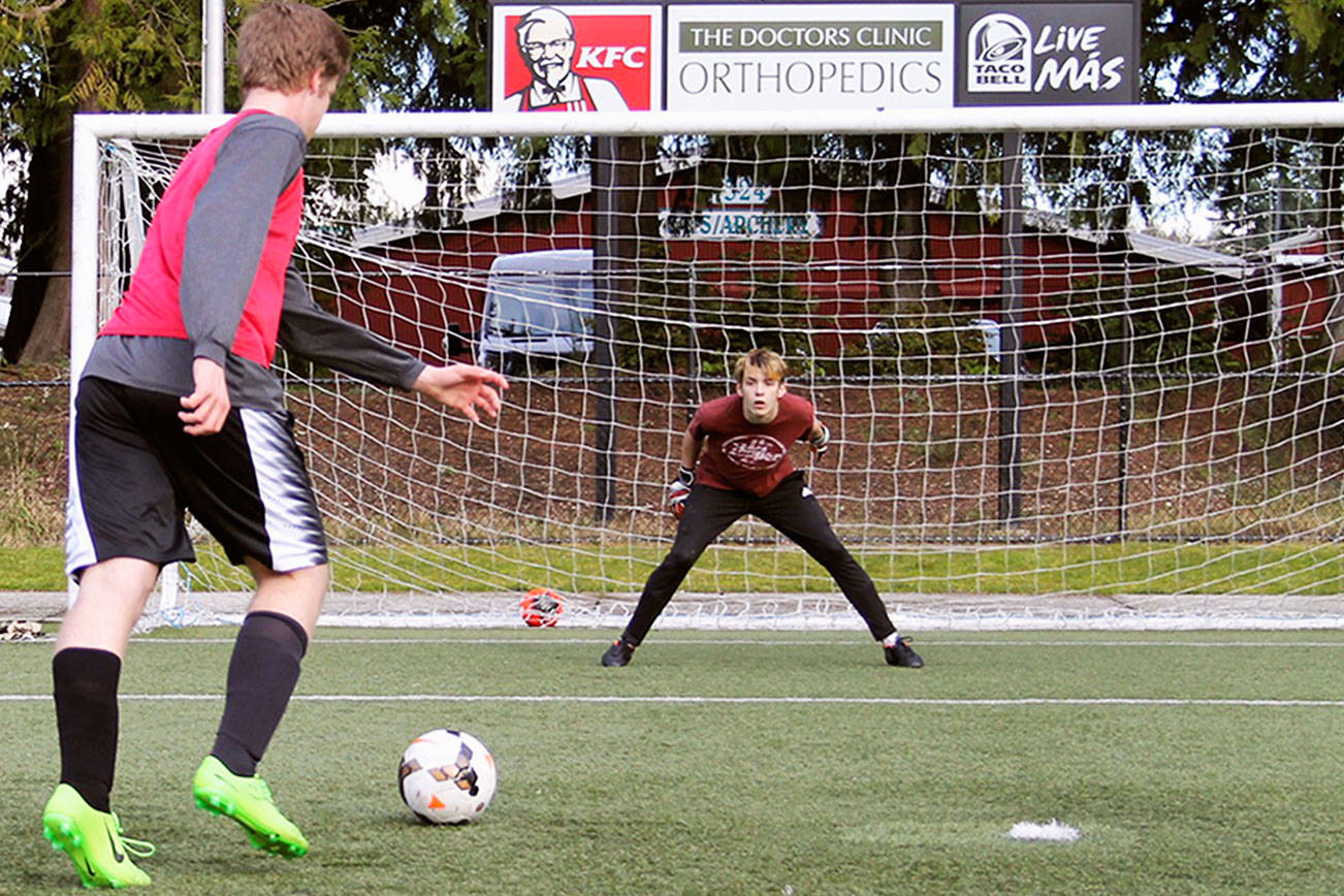 Ryan Geier, left, amps up before releasing a powerful shot toward goalkeeper Caden Kinsfather during a March 9 practice at Gordon Field. Jacob Moore | Kitsap News Group