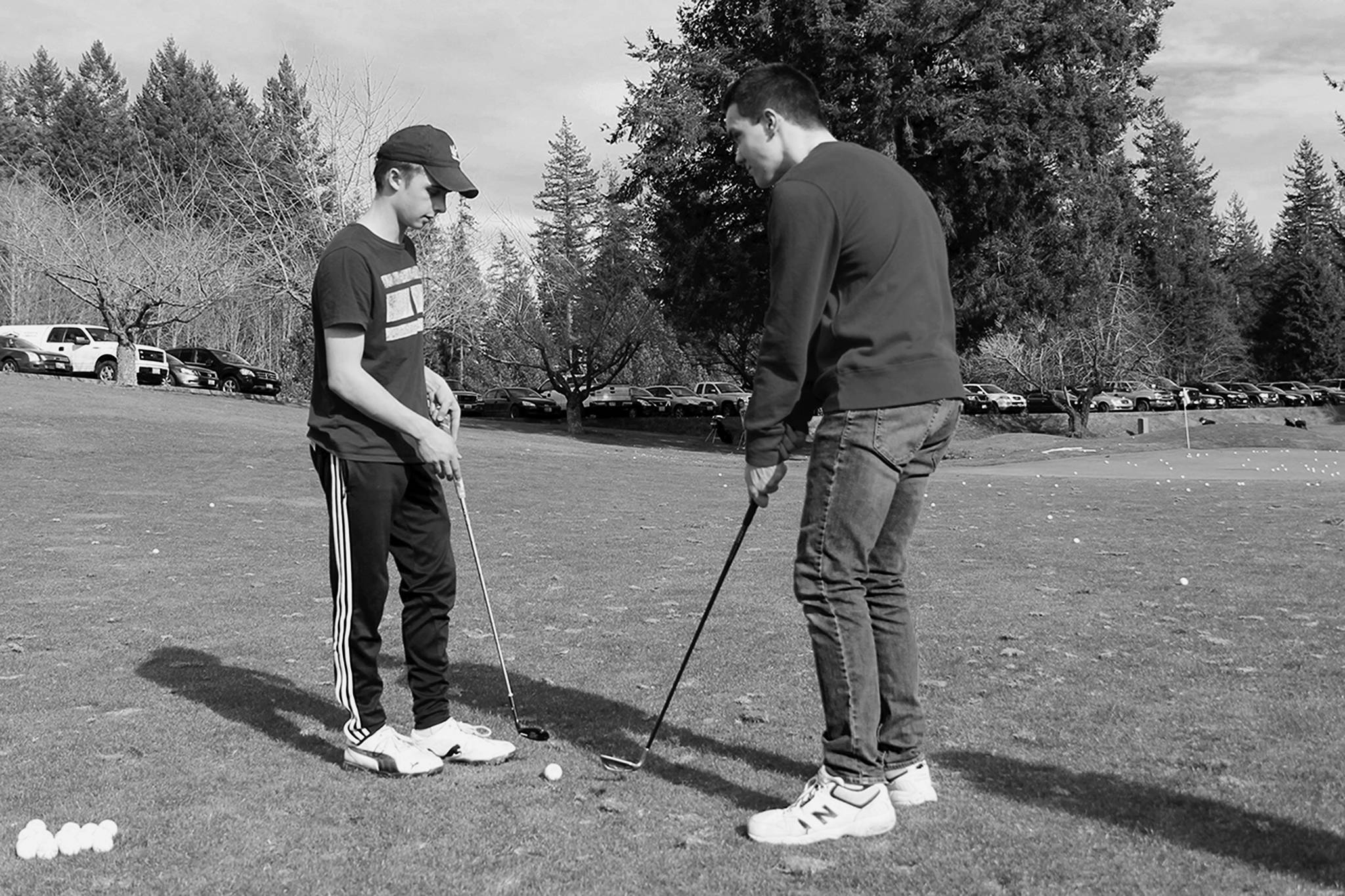 Senior Bryce Kahle, left, helps freshman Mathew Quall during practice at Gold Mountain Golf Course on March 12. (Jacob Moore/Kitsap News Group)