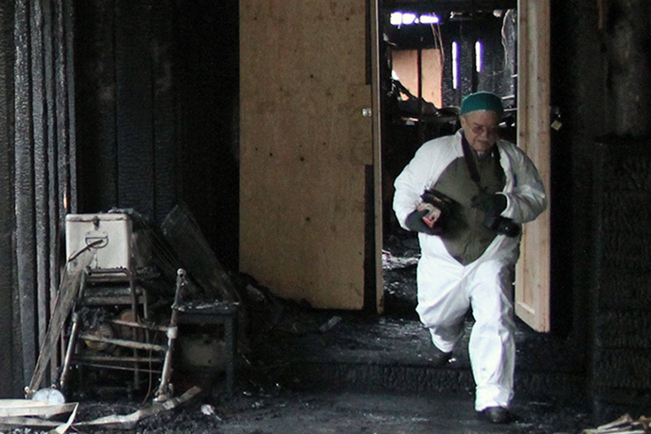 Walter Peale, walks out of what remains of his mother’s house, carrying some personal belongings. Jacob Moore | Kitsap News Group