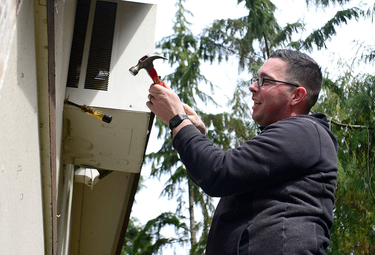 Aviation Electronics Technician 1st Class Charles Gimiro removes an air conditioning unit during the First Class Petty Officer Association outing April 18 at Stillpointe Llama Sanctuary in Seabeck.