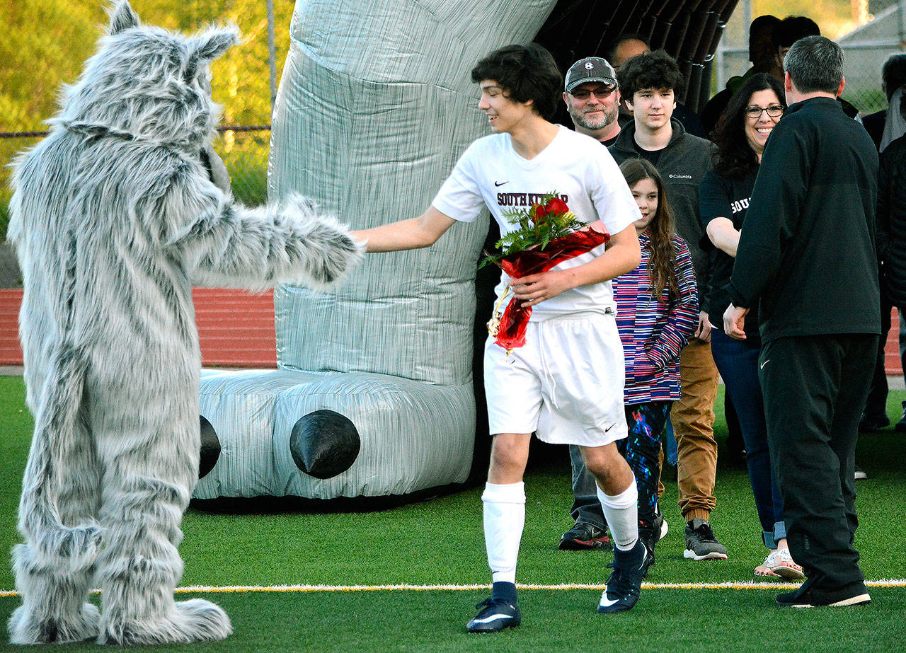 Colin Nuss gets a high-five from the Wolves’ mascot as he enters the field on Senior Night May 2.                                 Mark Krulish | Kitsap News Group