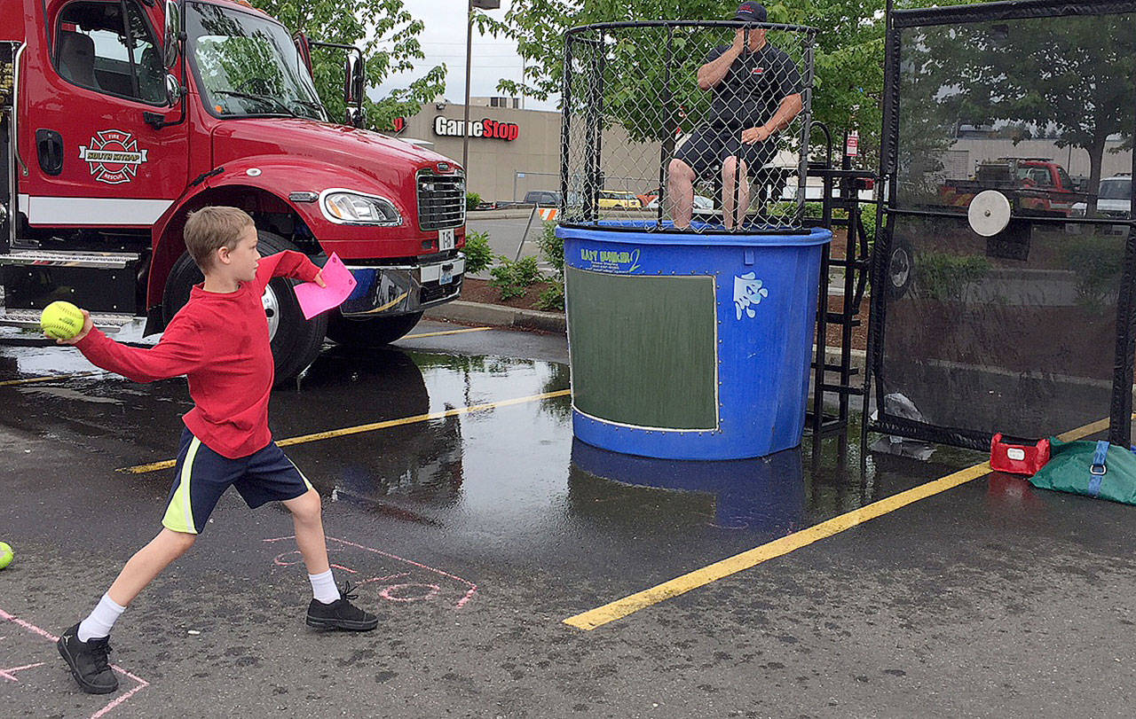 Deputy Chief Guy Dalrymple of South Kitsap Fire and Rescue gets ready to be dunked following a spot-on throw by this youngster at the May 19 Safety and Bicycle Rodeo event in Port Orchard. (Bob Smith | Kitsap Daily News)