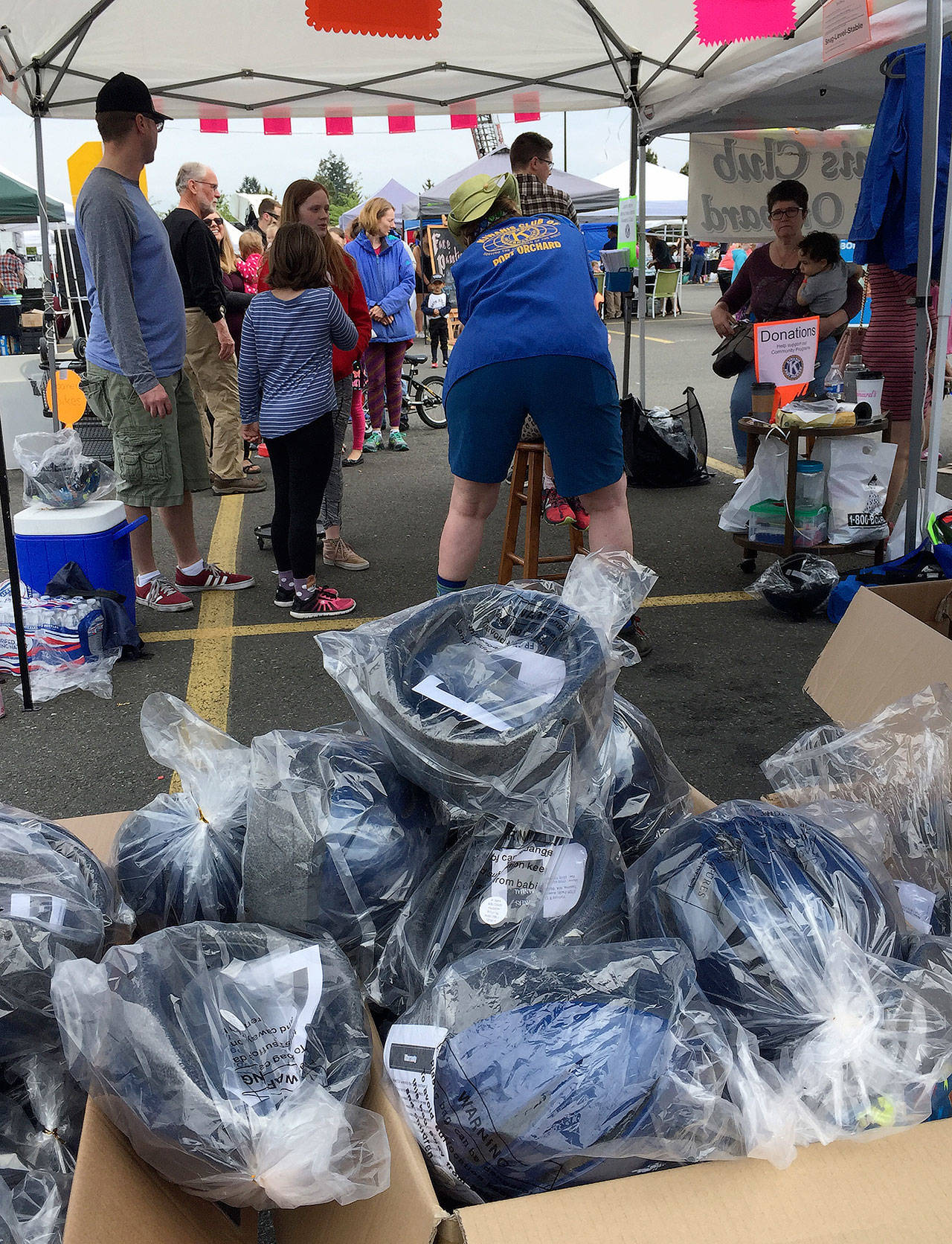Hundreds of new bicycle helmets (in the foreground) wait to be handed out to children after they are fitted for the proper size at the Safety Fair and Bicycle Rodeo May 19 in Port Orchard. (Bob Smith | Kitsap Daily News)