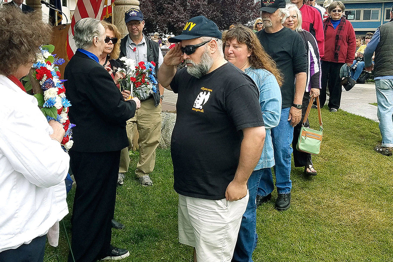 Rick Eckert, a retired Chief Petty Officer, salutes the wreath after he places a flower at Poulsbo’s Memorial Day ceremony. (Mark Krulish/Kitsap News Group)