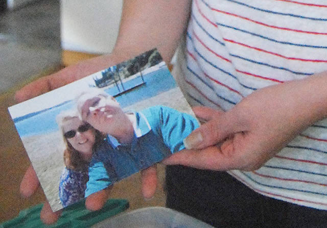 Tawnie Ploe, daughter of hit-and-run victim Michael Keaton, finds a photo of her father and mother while sorting through old images. (Bob Smith | Kitsap Daily News)