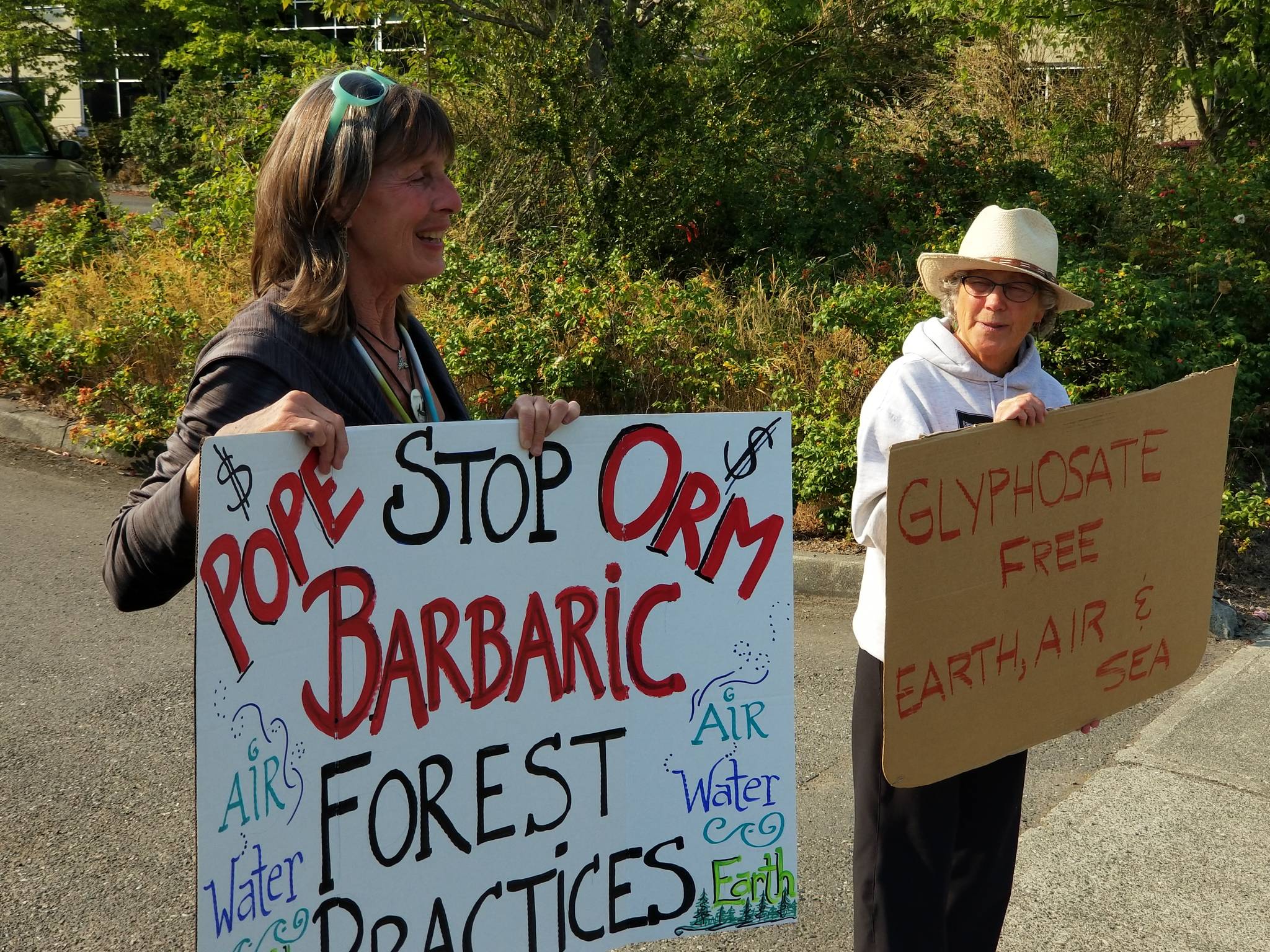 Wendy Heins Wrinkle and Barbie Brooking hold signs outside of Olympic Resource Management’s offices in Poulsbo. Nick Twietmeyer | Kitsap News Group
