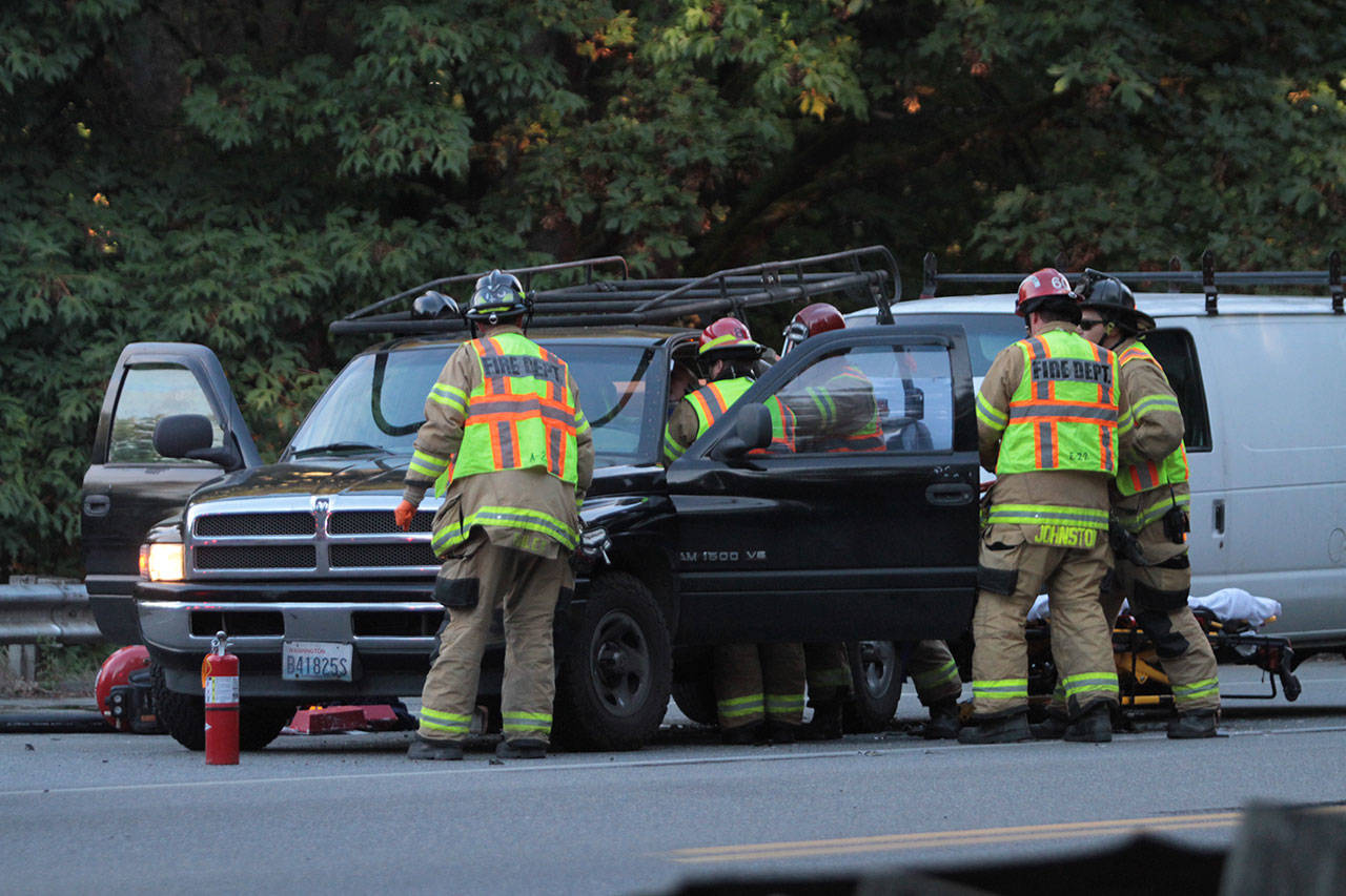 Bainbridge Island firefighters work to remove an injured driver from his pickup truck after a two-vehicle crash on Highway 305 on North Bainbridge Monday morning. (Brian Kelly | Bainbridge Island Review)