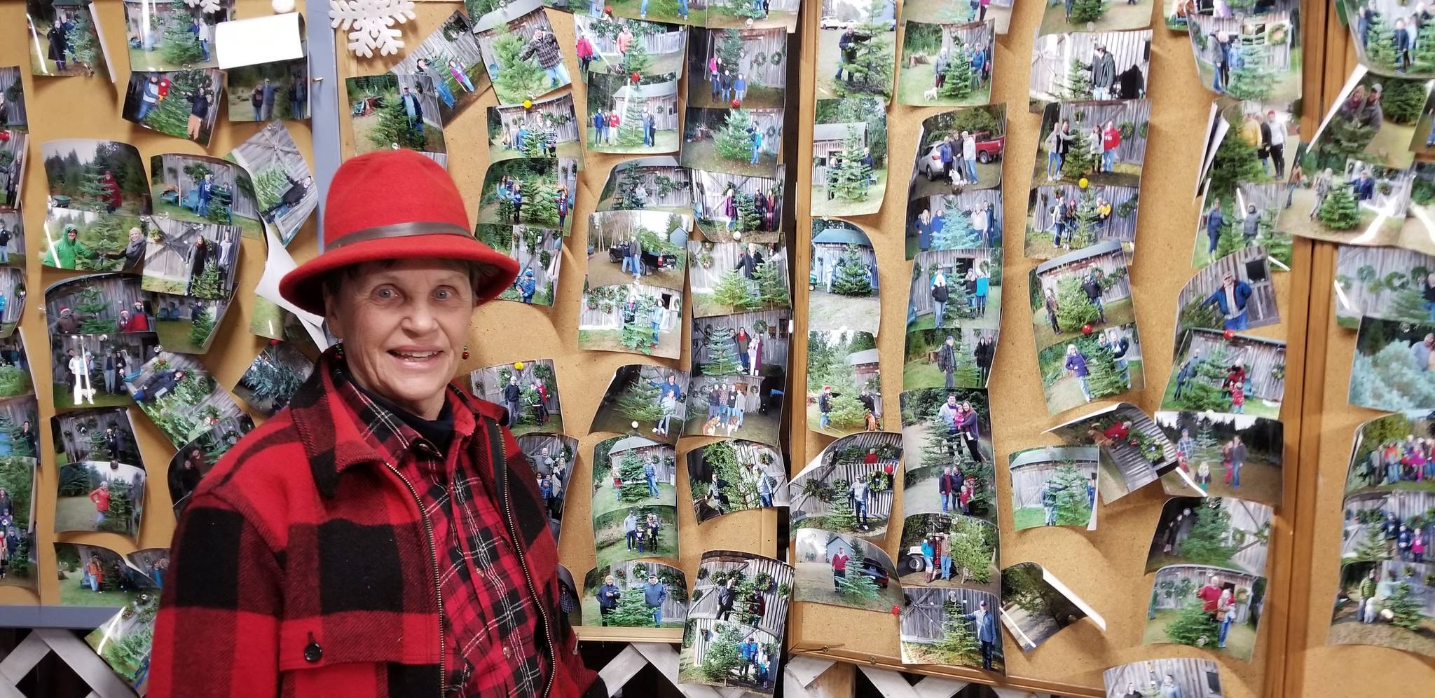 Elda Armstrong showcases her “gallery.” Each visitor that purchases a Christmas tree from St. Mick’s has their photo taken and placed on a wall for display next year. Nick Twietmeyer / Kitsap News Group