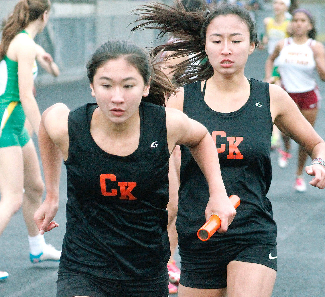 Maya Nichols hands off the baton to her younger sister, Taylor, in the 4x400 relay. (Mark Krulish/Kitsap News Group)