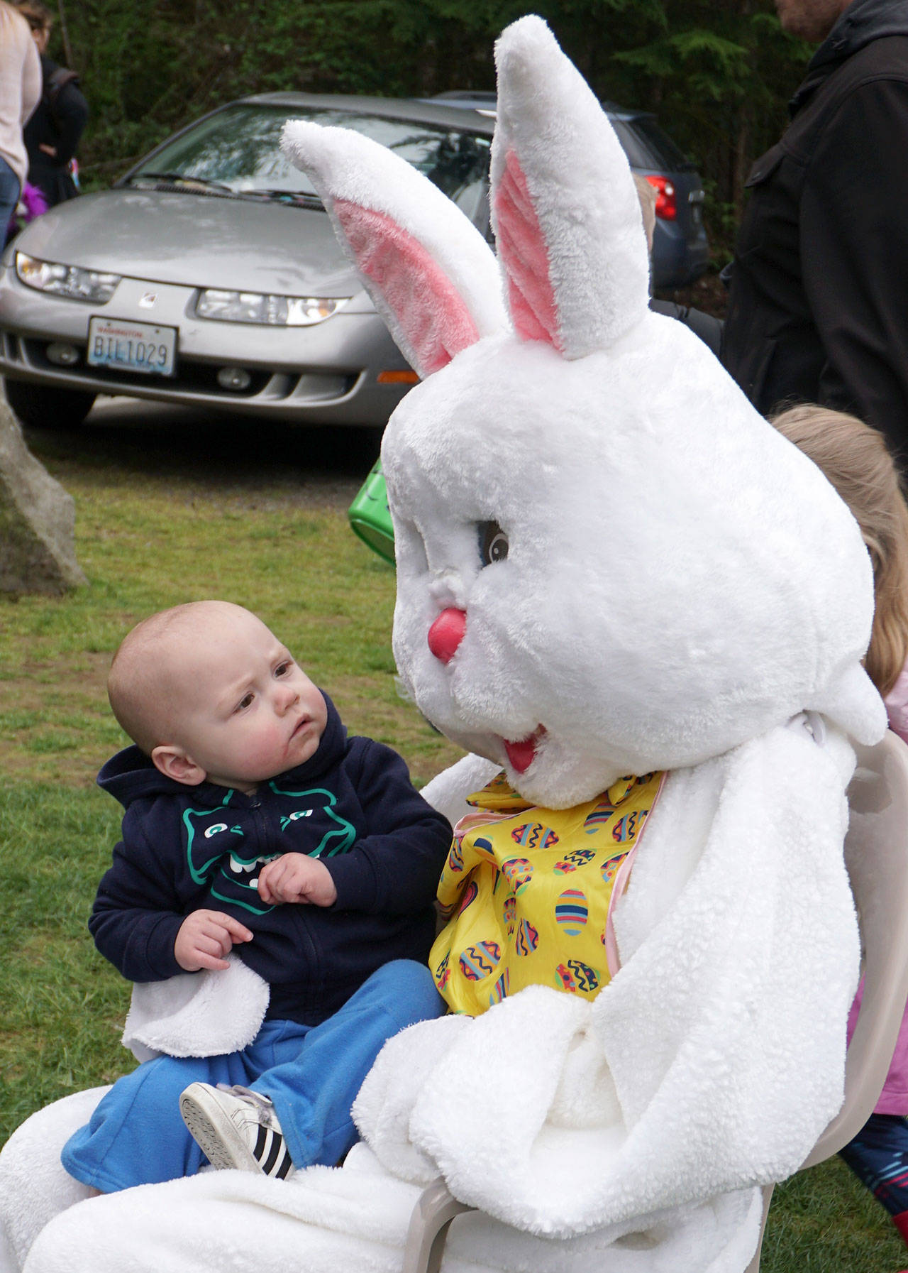 A tiny one gives the Easter Bunny a quizzical glance before Dad takes a photo. (Bob Smith | Kitsap Daily News)