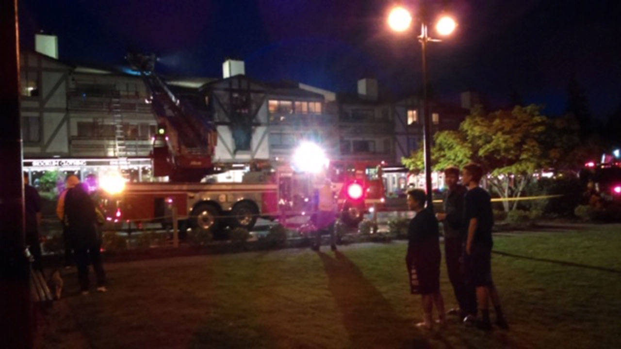 Onlookers watch as emergency crews respond to a fire at Winslow Green Thursday night. (Luciano Marano | Bainbridge Island Review)