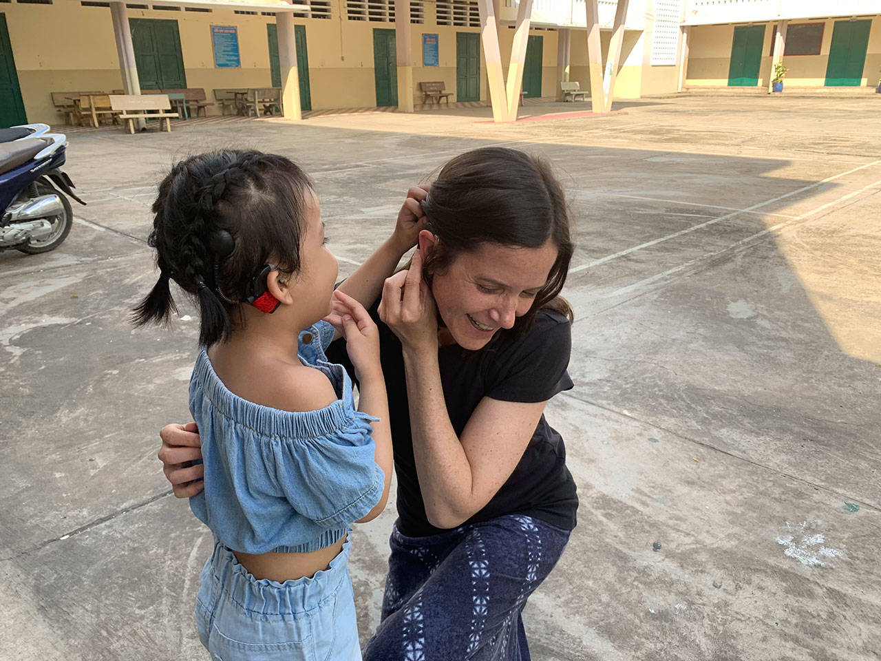 Paige Stringer shows her own hearing aids to Mongolian child.