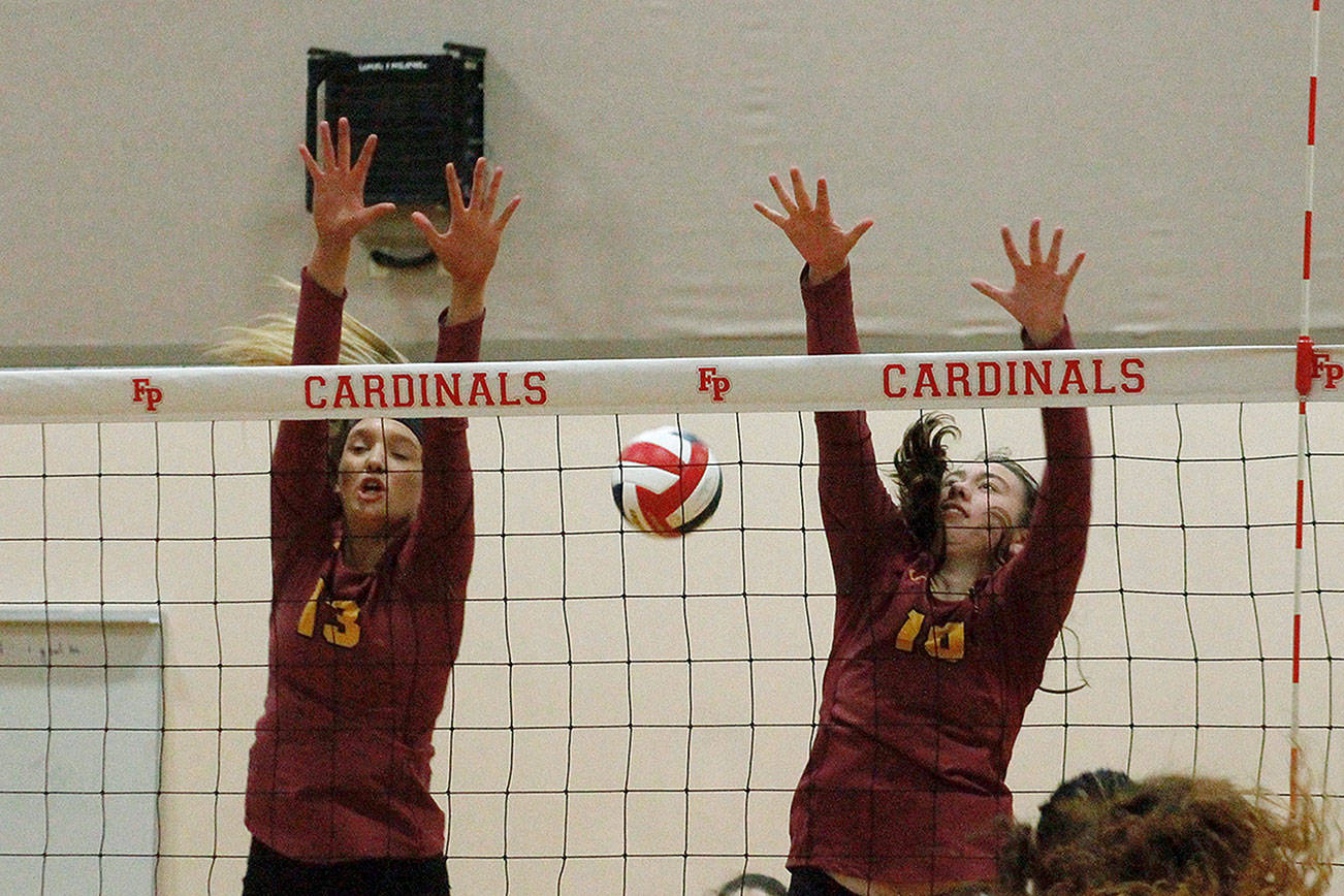 Morgan Halady (13) and Abby Steele (10) of Kingston team up for a block attempt against Fife. (Mark Krulish/Kitsap News Group)
