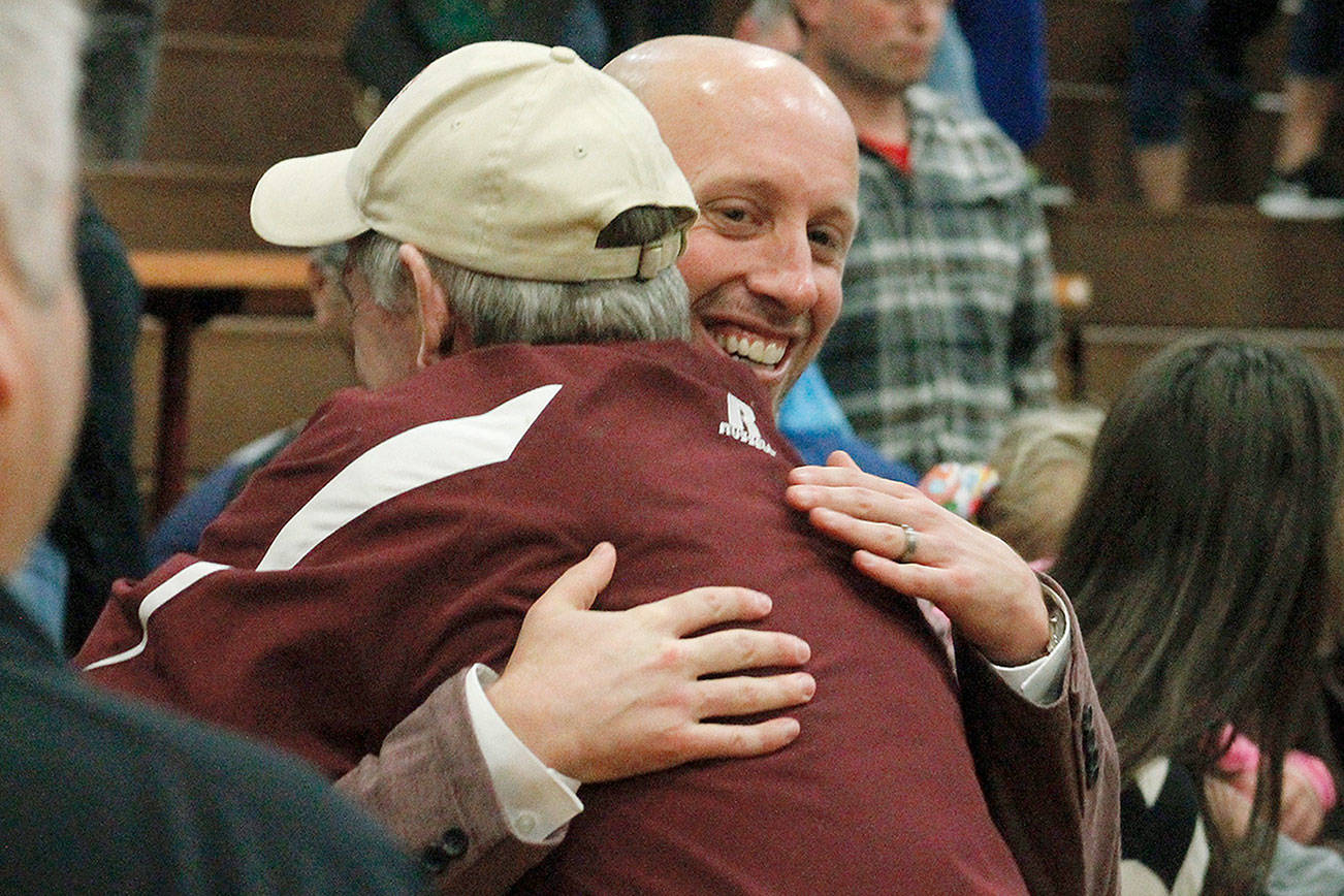 Brian Cox gets a congratulatory hug after picking up his first career win as head coach on opening night. (Mark Krulish/Kitsap News Group)
