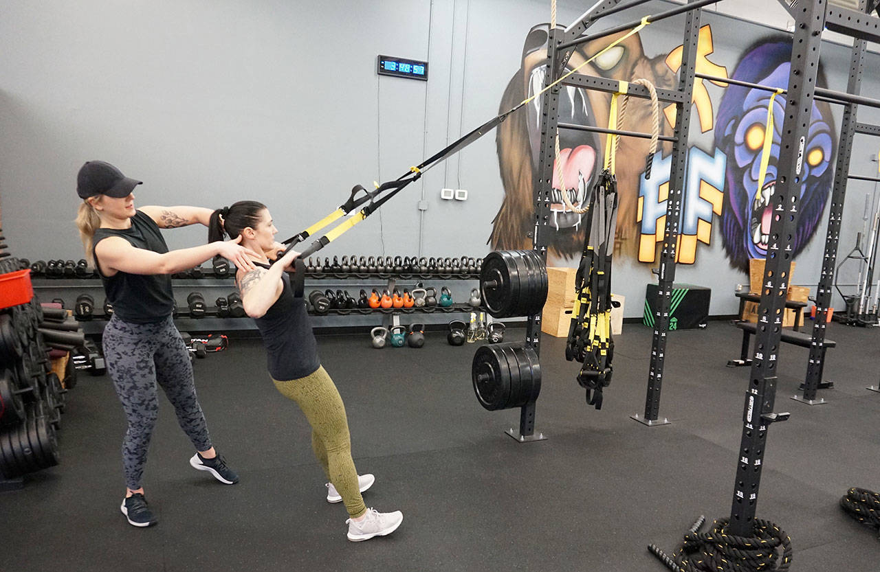 Annapolis Fitness Performance co-owners Sydnie Kittelson (left) coaches Kristi McGee on a TRX row. (Mike De Felice photo)