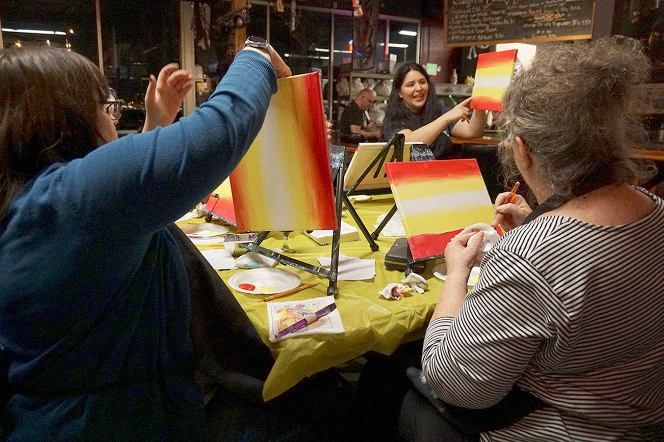 These beginner painters follow instructor Danielle Rimbert’s directions as they put down colors depicting their painting’s background. (Bob Smith | Kitsap Daily News)