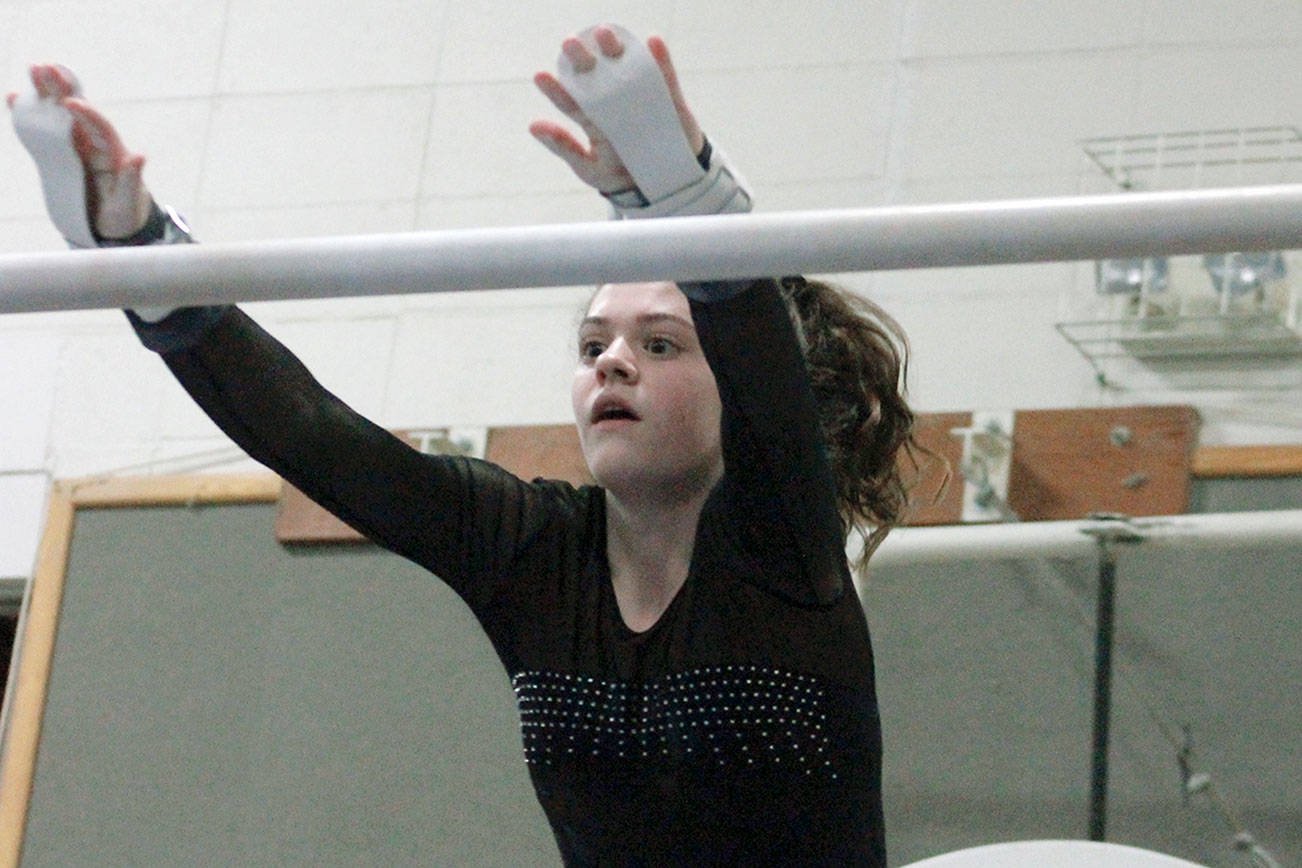 North Kitsap’s Alivia Palmer makes a leap for the high bar during a dual meet against Kingston. (Mark Krulish/Kitsap News Group)