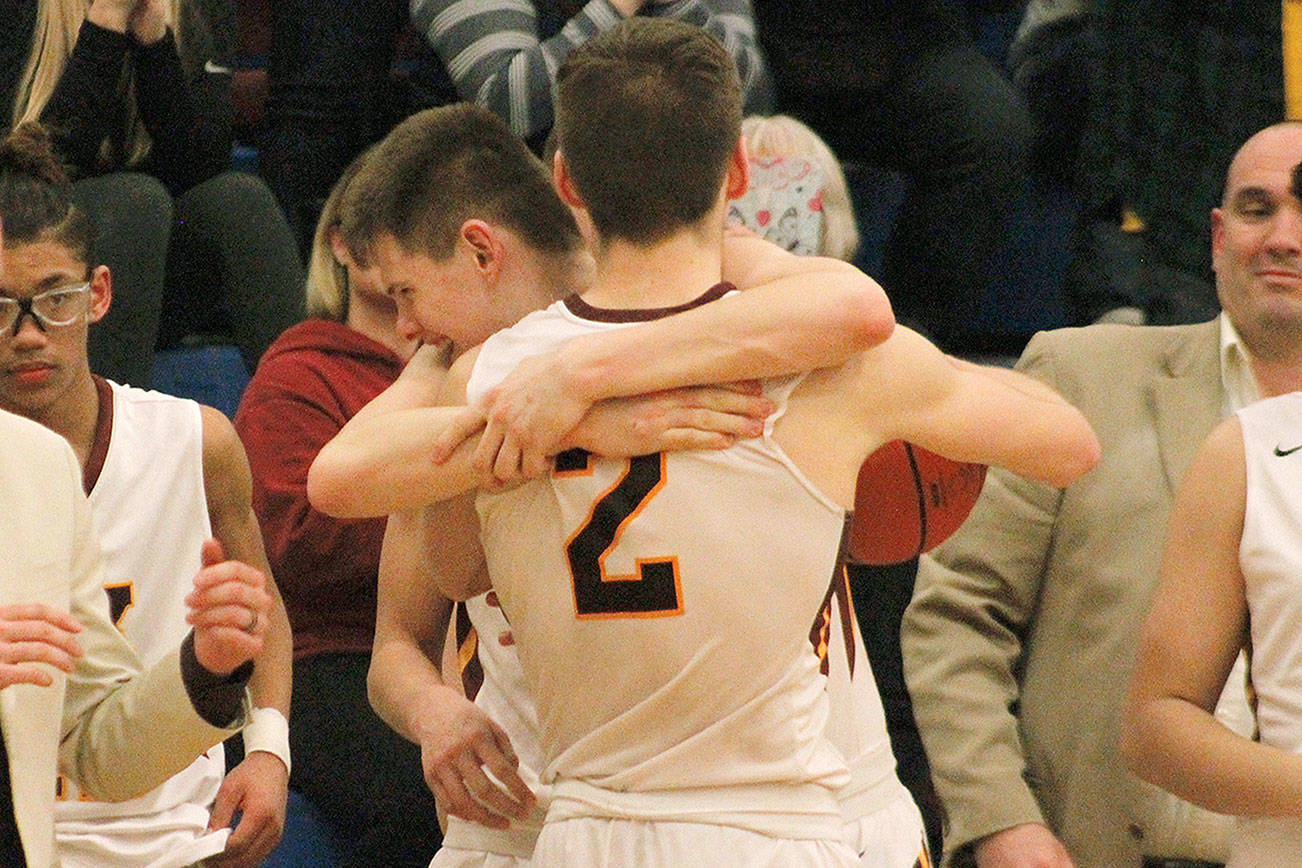 Gavin Morkert (2) receives a warm welcome at the bench from Jack Kees (14) shortly after the final buzzer sounded and South Kitsap defeated Rogers 64-52 at the 4A West Central/Southwest bi-district tournament. (Mark Krulish/Kitsap News Group)