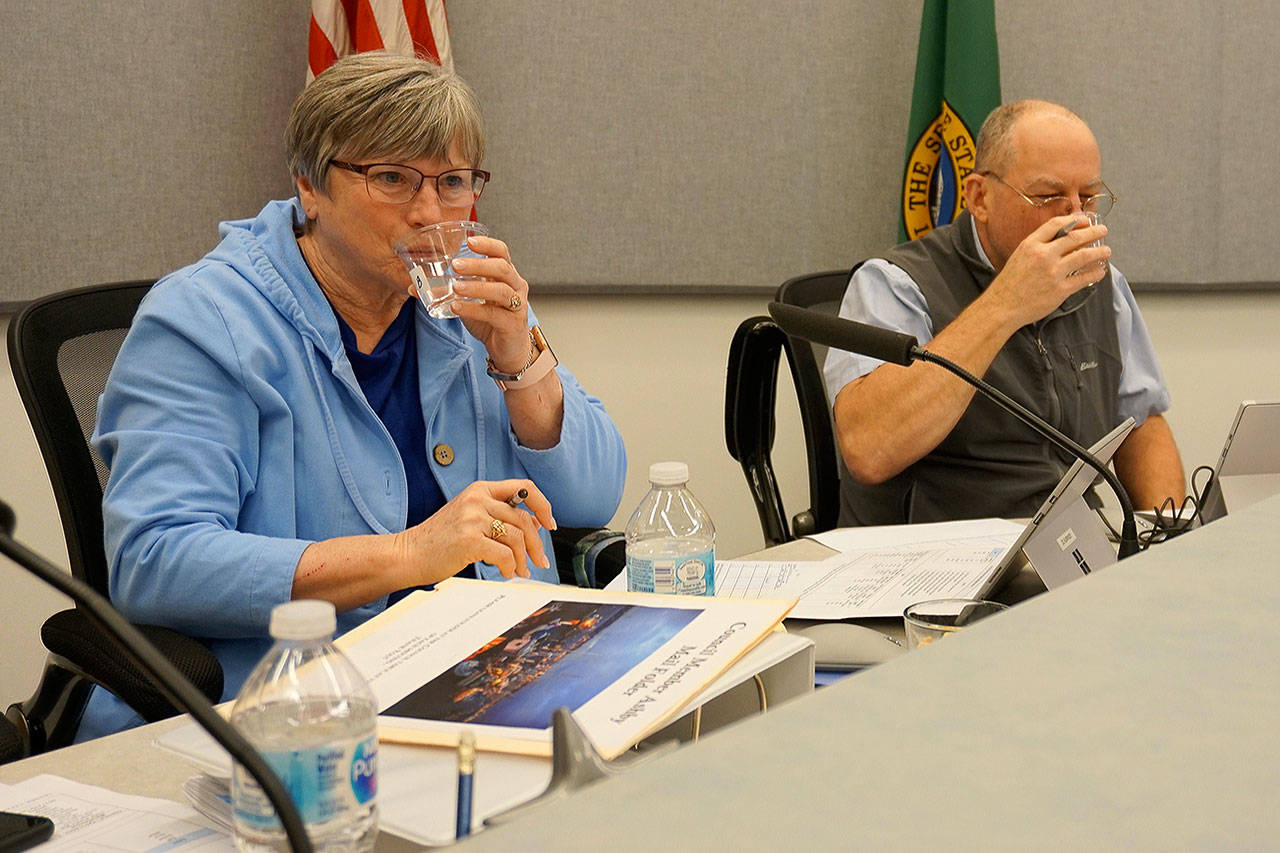 Port Orchard City Council members Bek Ashby (left) and Jay Rosapepe sip water samples from four city water sources. (Bob Smith | Kitsap Daily News)